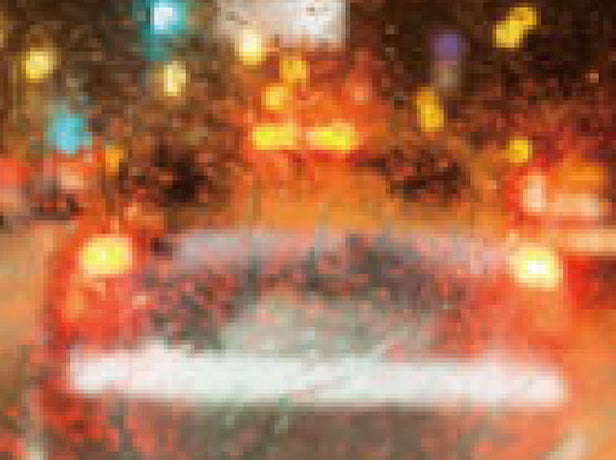 photo shot from inside a car showing the front glass obscuring the car in front of it due to water bands on the glass